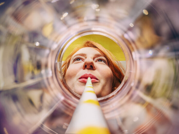 Sich aus einem leeren Glas entlang eines Strohhalms auf ein weibliches Gesicht