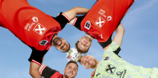 Vier Fußballspieler stecken die Köpfe zusammen.