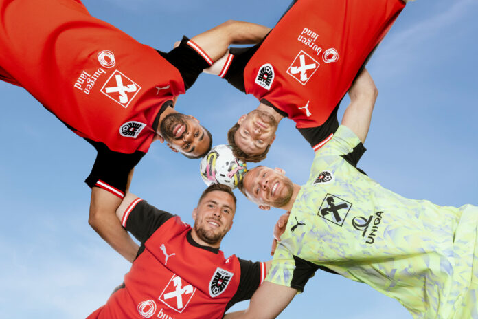 Vier Fußballspieler stecken die Köpfe zusammen.