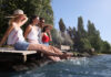 Drei Frauen und ein Mann sitzen auf einem Steg und lassen die Beine ins Wasser hängen