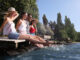 Drei Frauen und ein Mann sitzen auf einem Steg und lassen die Beine ins Wasser hängen
