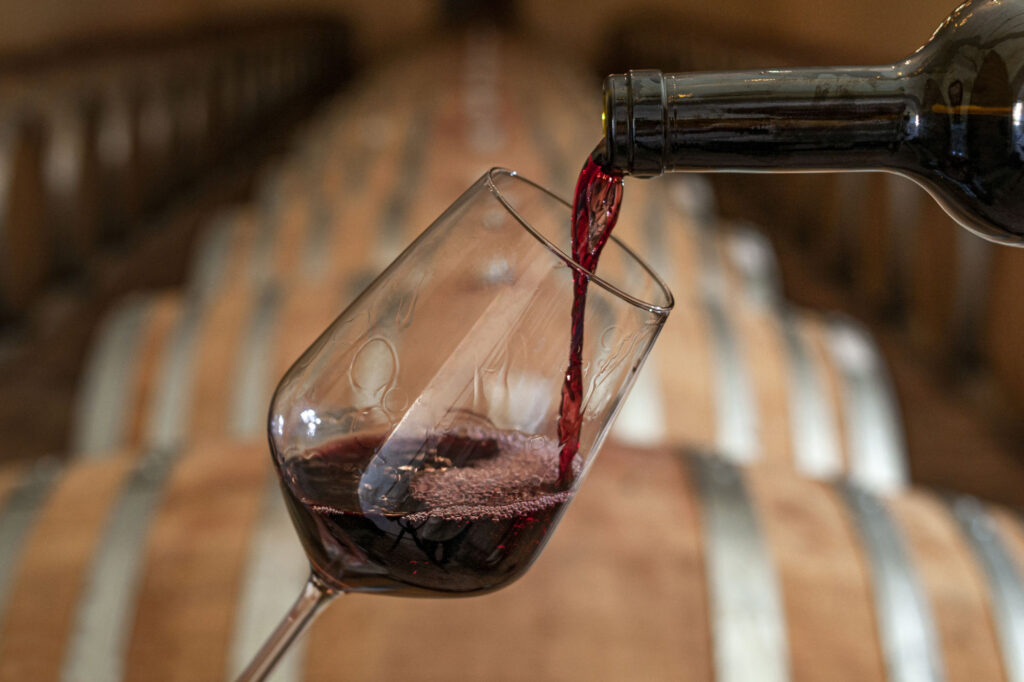 Detailaufnahme: Rotwein wird in ein Weinglas geleert.