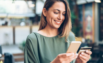 E-Commerce: Das Smartphone als Einkaufswagen Frau mit einem Smartphone und einer Kreditkarte in der Hand