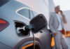 Elektromobilität zwischen Rückenwind und Steuerbremse A businessman phoneing while charging car at electric vehicle charging station, closeup.
