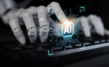 Roboterhand auf einer Tastatur, Symbolbild KI