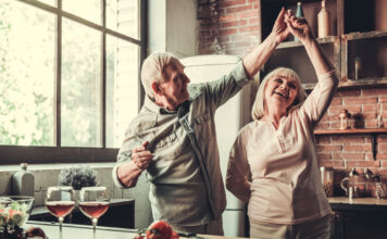 Mehr Zusatzpension! Älteres Paar tanzt fröhlich in der Küche. Symbolbild Zusatzpension, Pension, Ruhestand