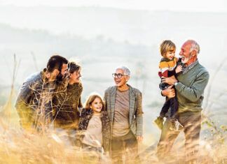 Happy multi-generation family talking while taking a walk on the field. Copy space.