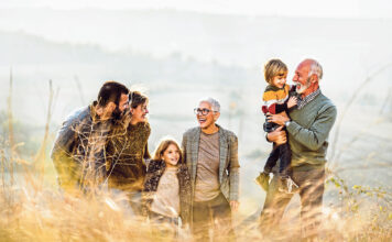 Happy multi-generation family talking while taking a walk on the field. Copy space.