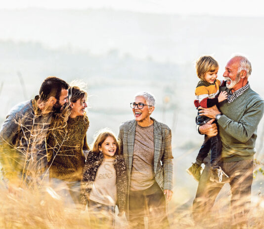 Happy multi-generation family talking while taking a walk on the field. Copy space.