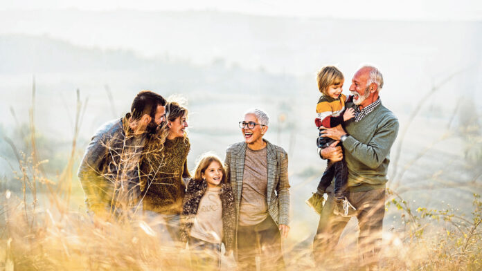 Happy multi-generation family talking while taking a walk on the field. Copy space.